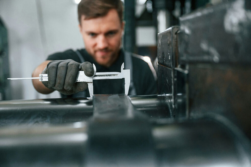 Man using a caliper tool to measure thickness of something.