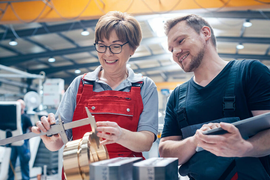 Man and woman using a caliper tool to measure item.